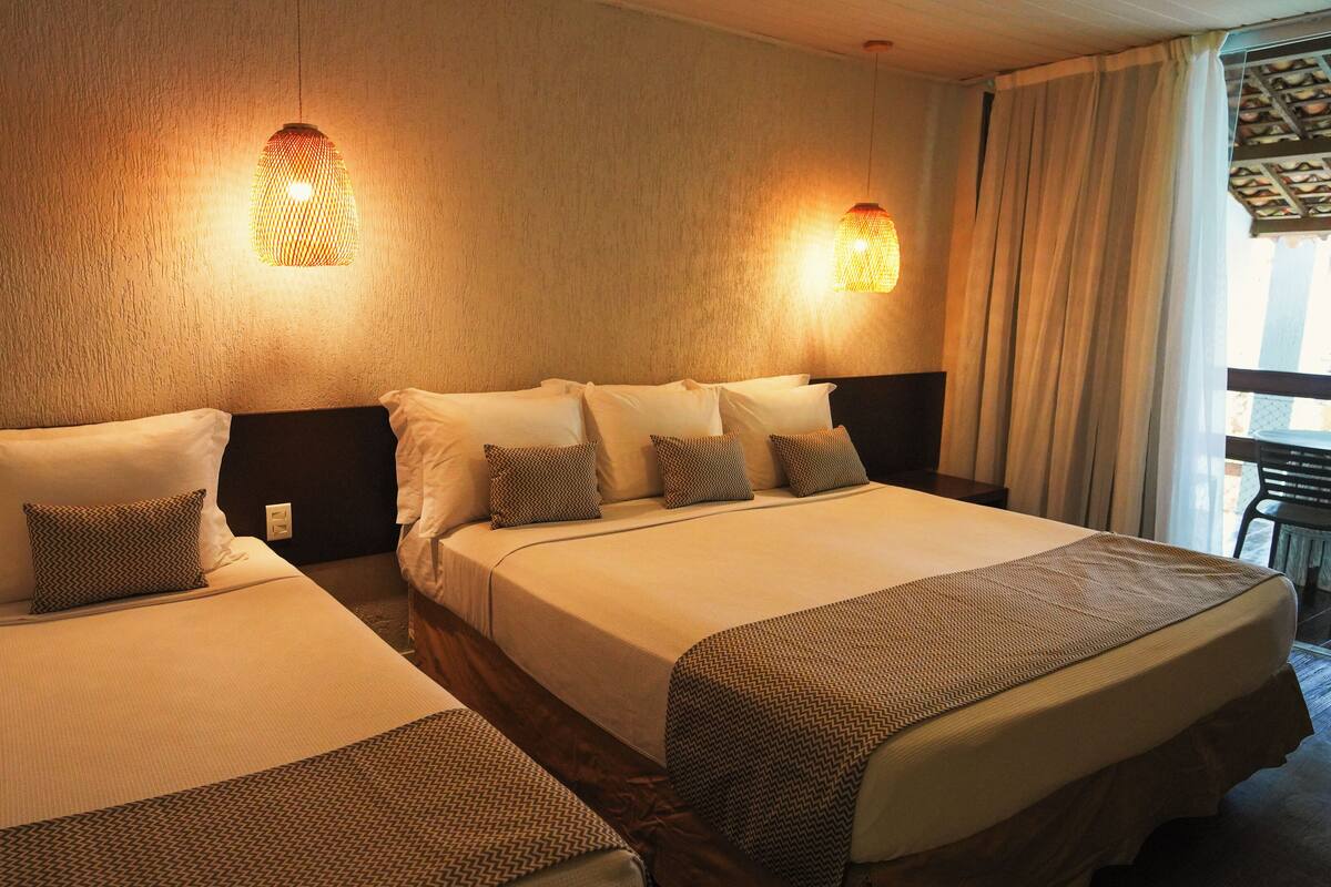 Ein Hotelzimmer mit zwei Betten, gemusterten Bettdecken und Wandleuchten.