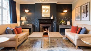 A living room with two sofas, a fireplace, and a chandelier. - Beaulieu Hotel (Brockenhurst)