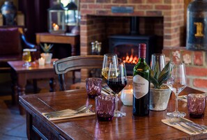 Una mesa de comedor dispuesta con copas de vino, una botella y una planta en maceta.