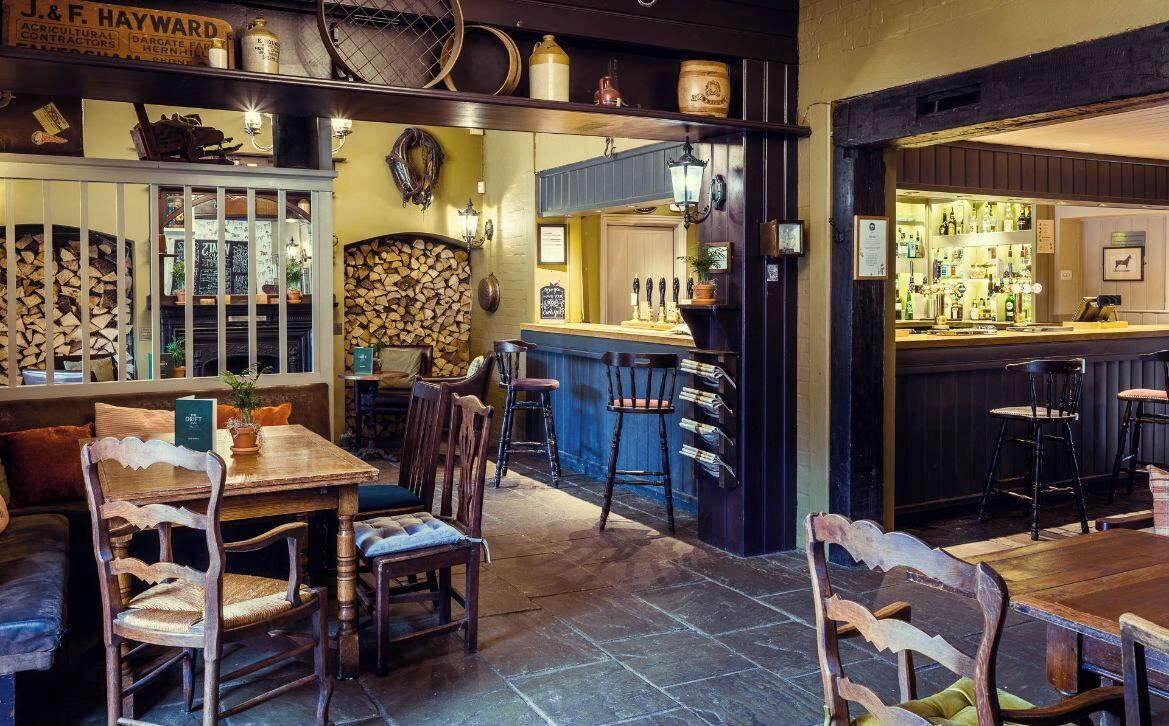 Un pub chaleureux avec des meubles en bois, un coin bar et un mur en pierre.