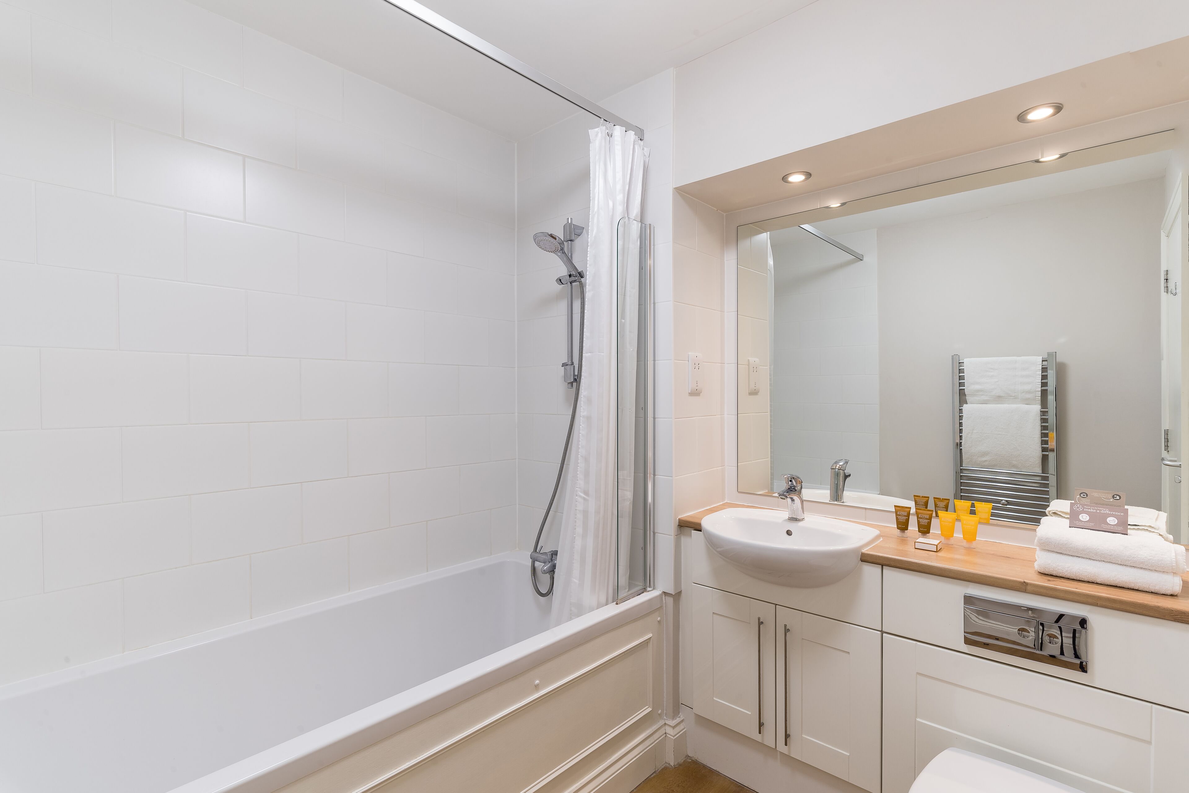 A modern bathroom with a bathtub, shower, sink, and vanity.