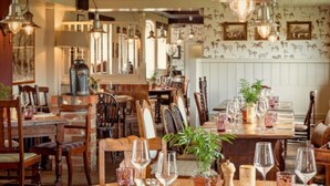 A restaurant with wooden tables, chairs, and hanging light fixtures. - Beaulieu Hotel (Brockenhurst)