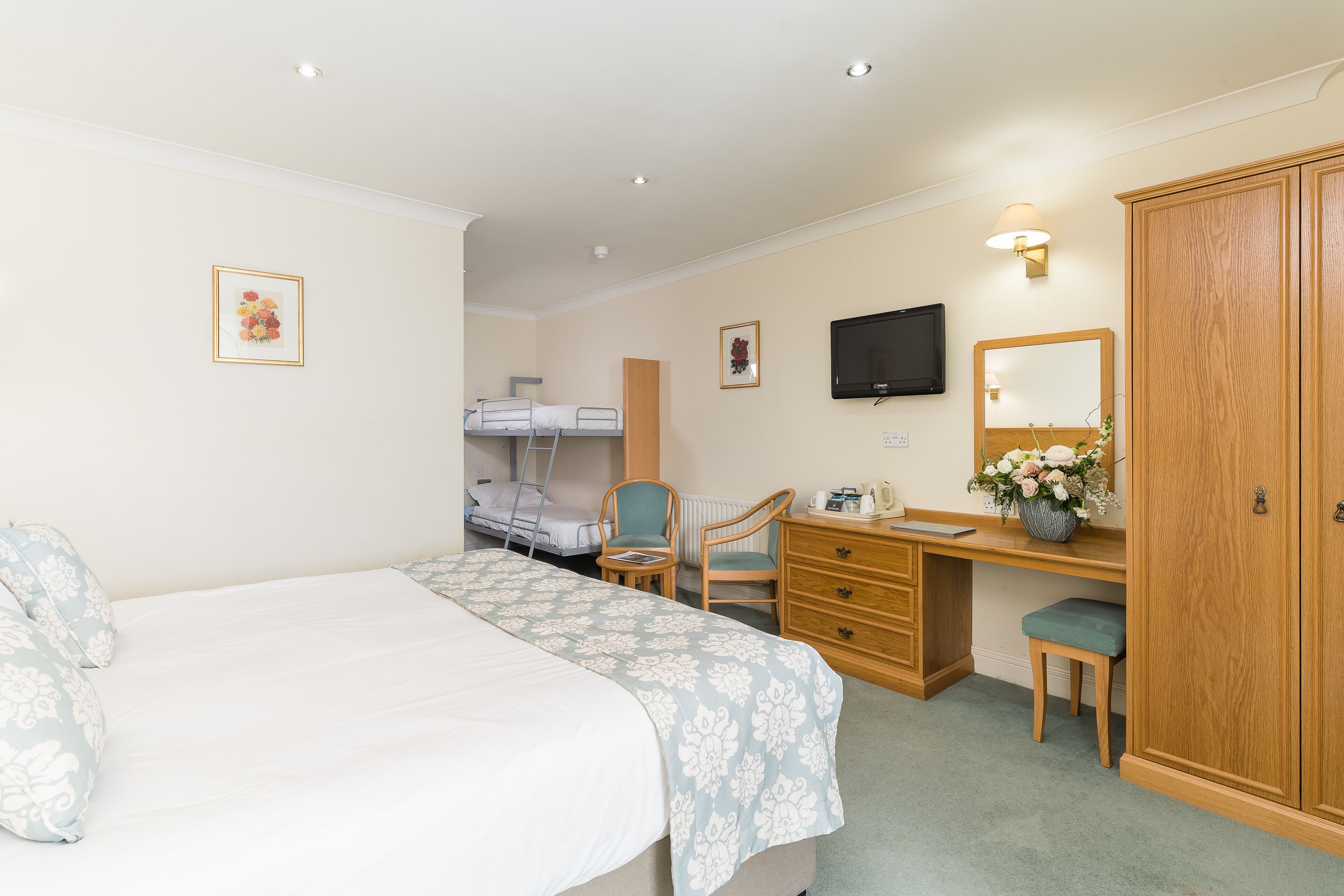 A hotel room with a bed, desk, chair, wardrobe, and a television.