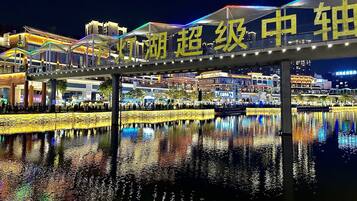 A nighttime view of a waterfront area with illuminated buildings and a pedestrian bridge.