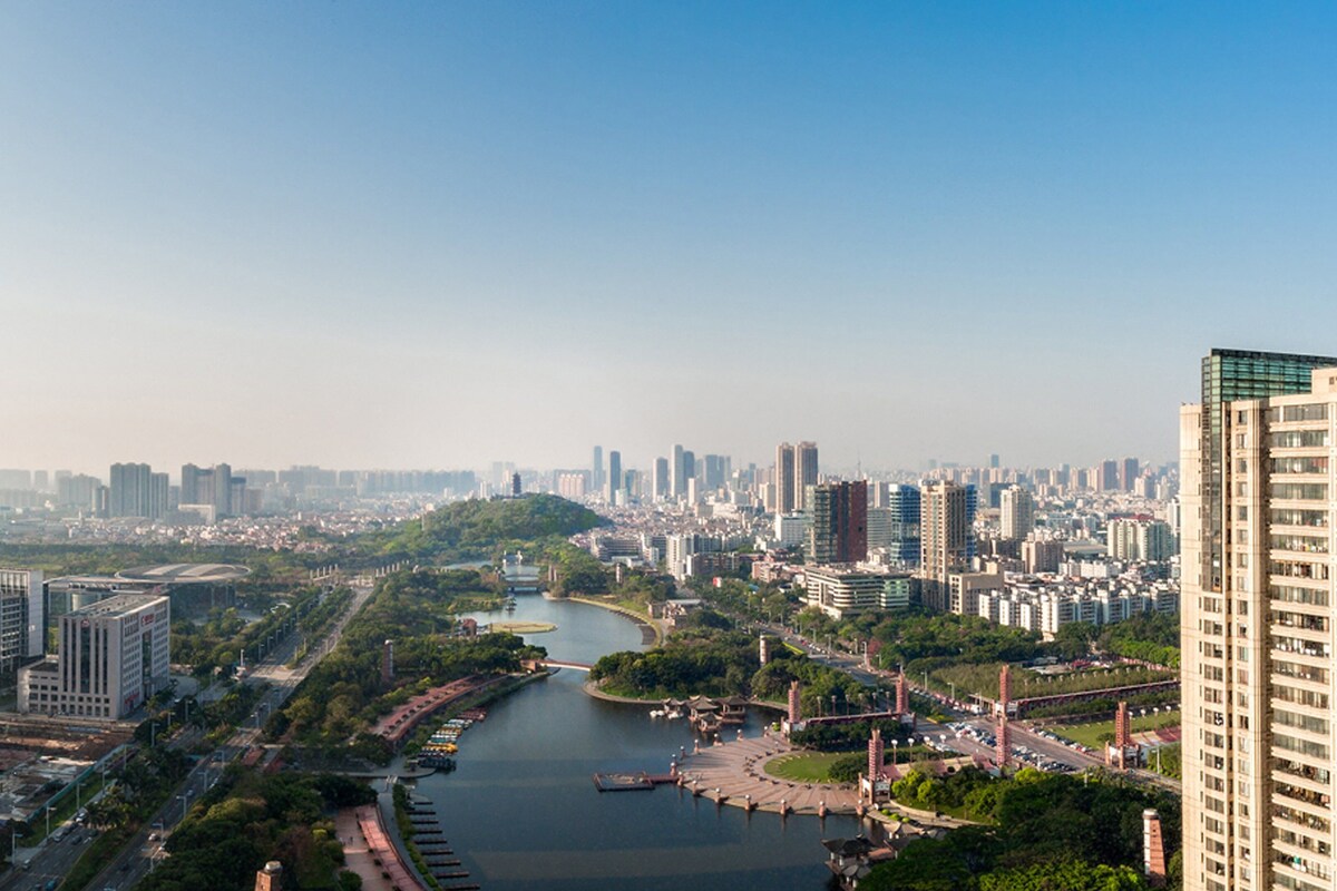 A cityscape with a river, high-rise buildings, and a park area.