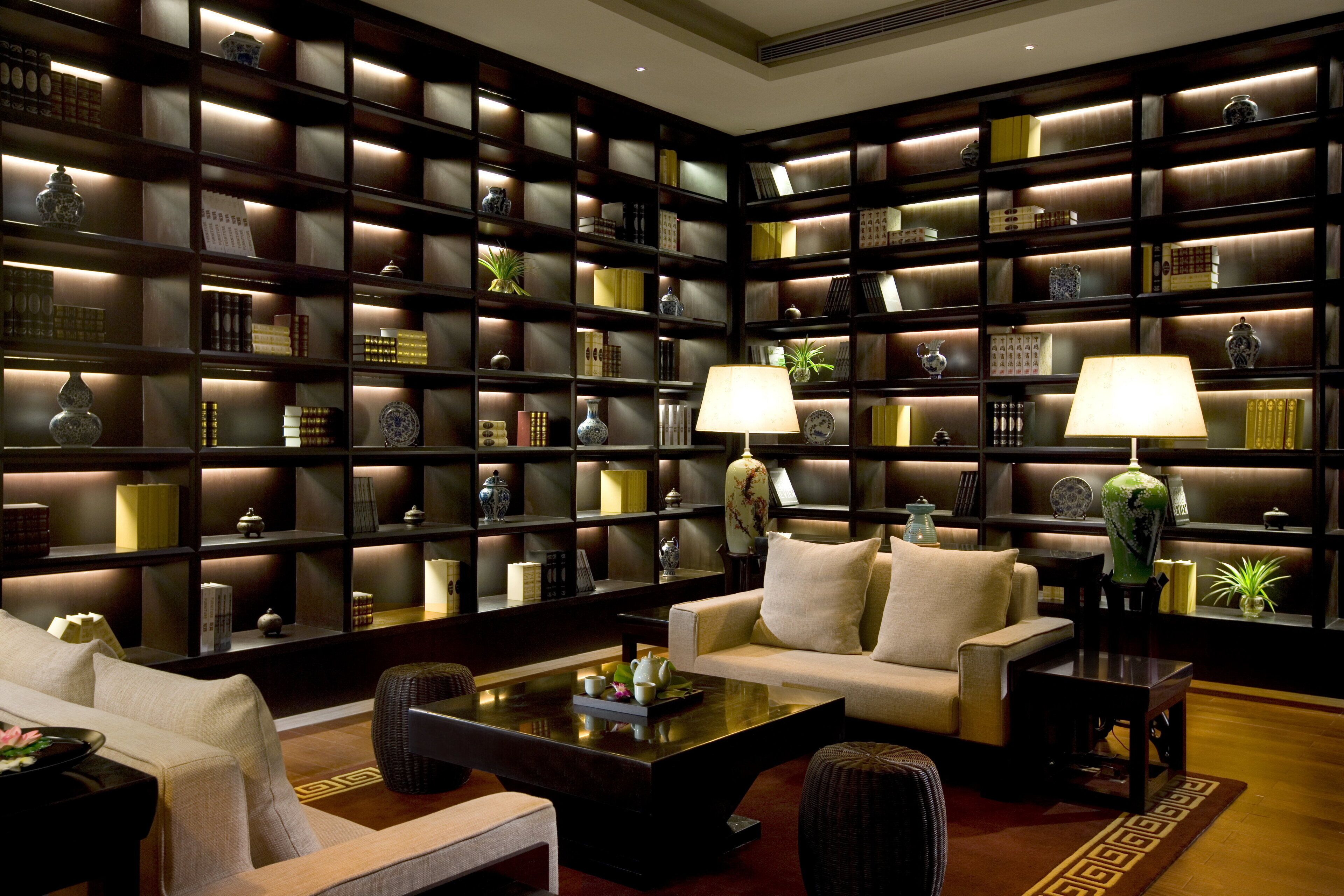 Een bibliotheek met boekenplanken, twee lampen en een bank.