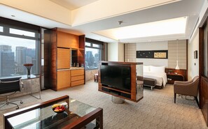 A modern hotel room with a large TV, a dining area with a glass table, a sofa, and a bed. - InterContinental Foshan by IHG (Foshan)