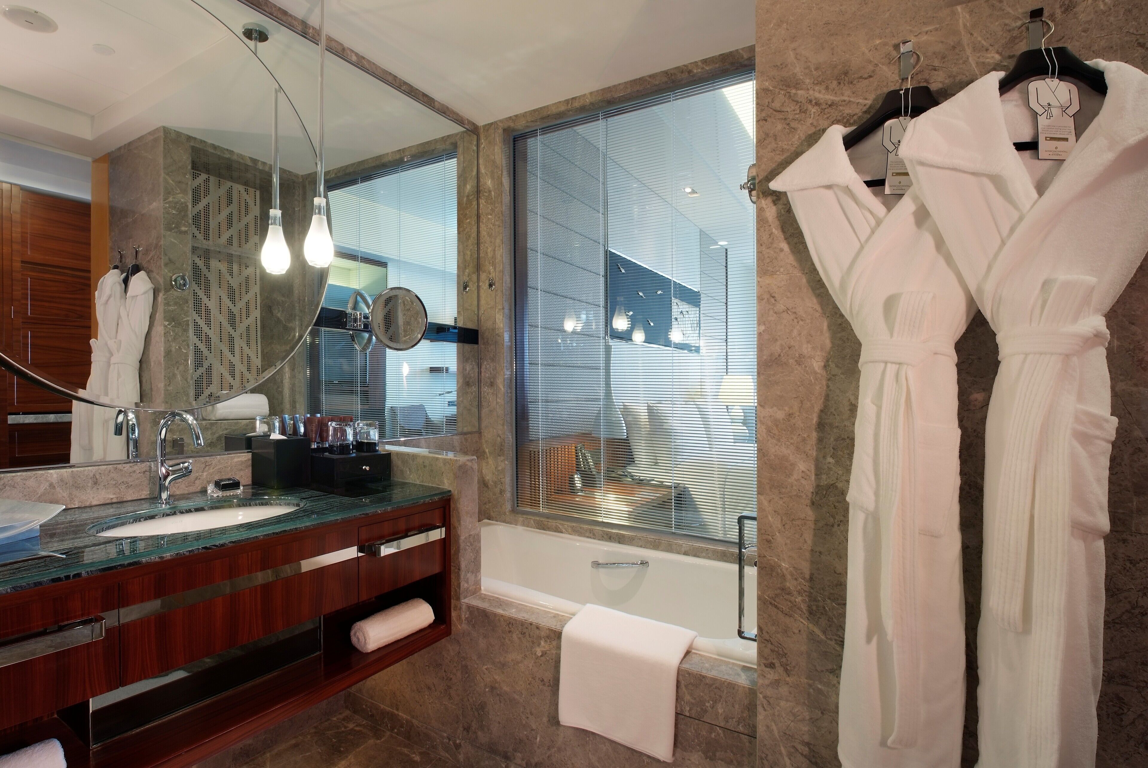 Un baño moderno con un lavabo de vidrio, un espejo grande y una bañera.