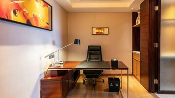 A modern office space with a desk, chair, lamp, and artwork on the wall.