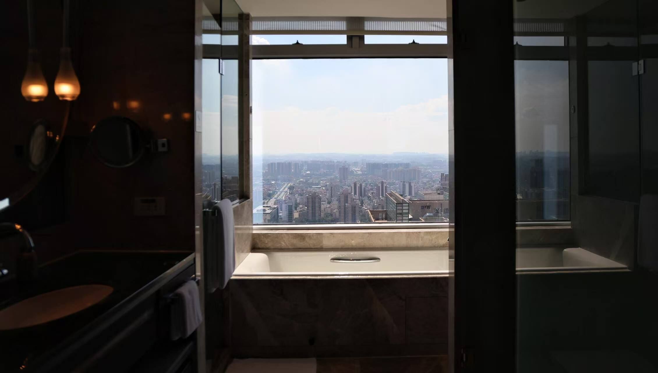 A bathroom with a large window offering a cityscape view.