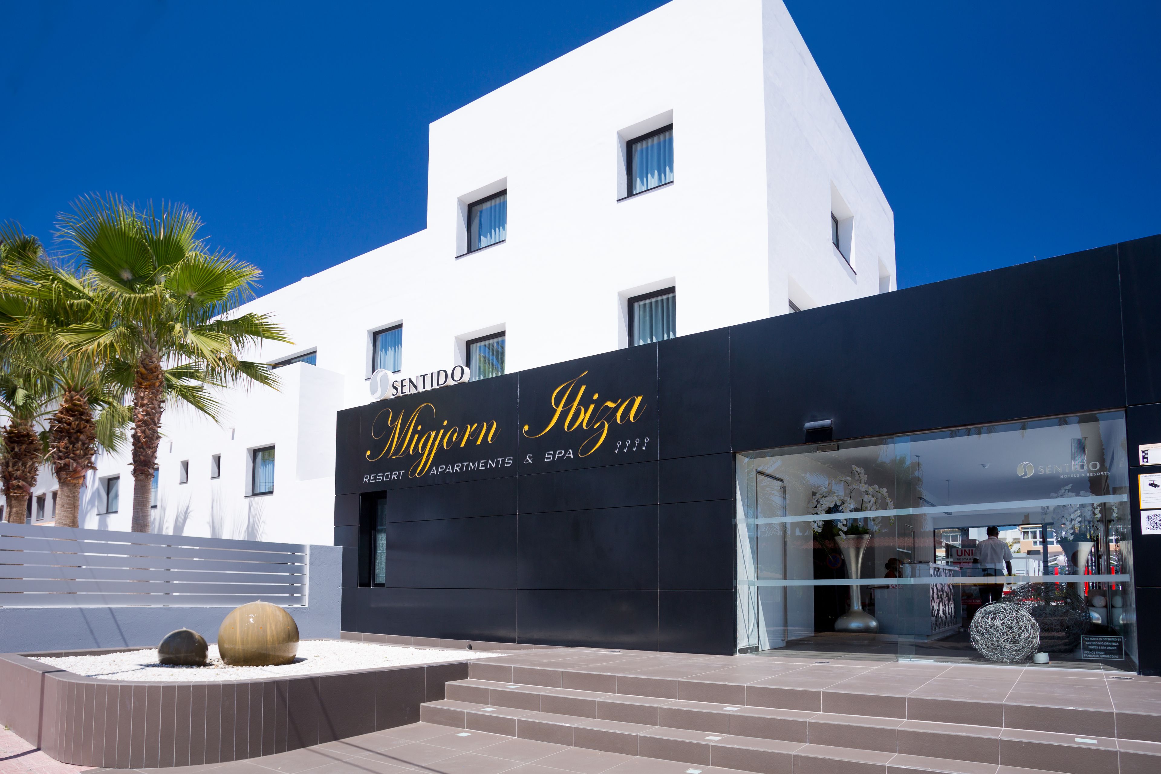 Ein modernes Gebäude mit einem Schild für 'Migorn Ibiza' und 'Sentido Residences & Spa'.