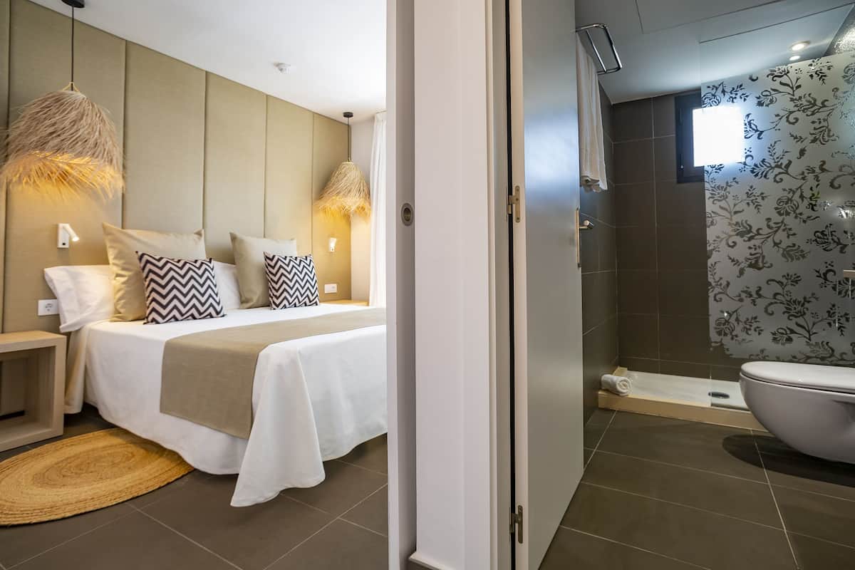 A modern bedroom with a bed, bedside tables, and a hanging light fixture.