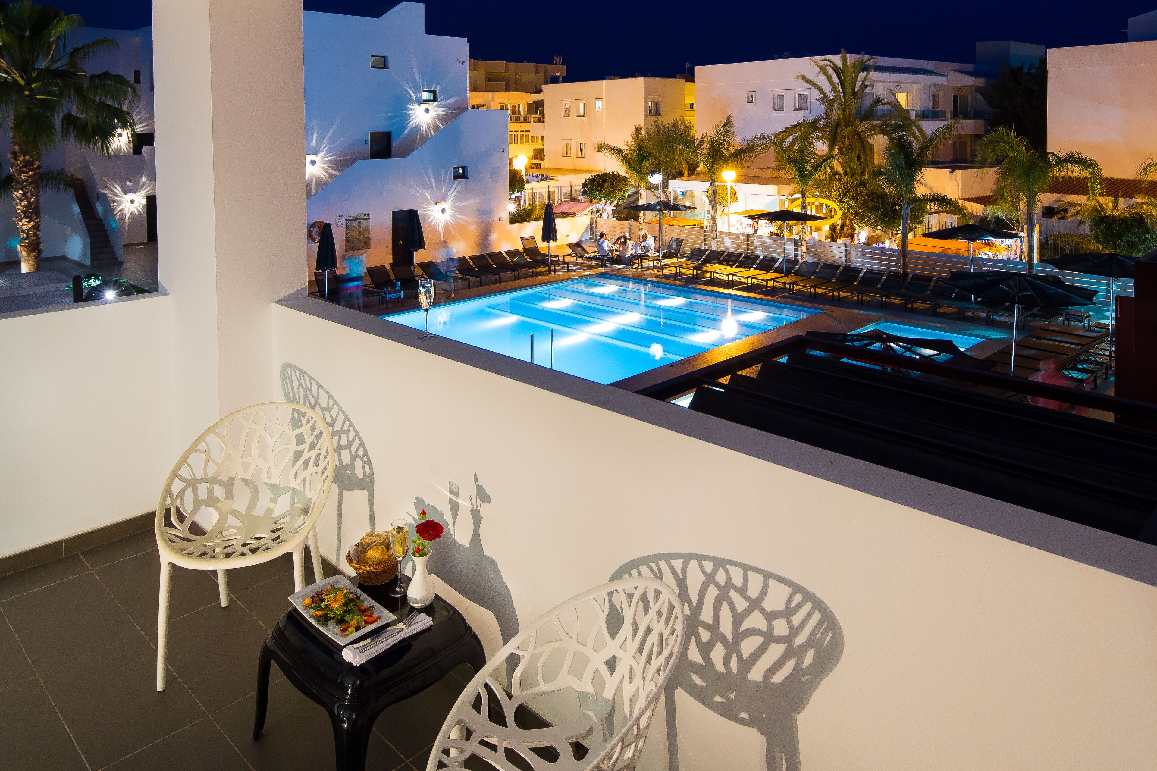 Un área de piscina en la azotea con sillones de descanso y mobiliario para comer.