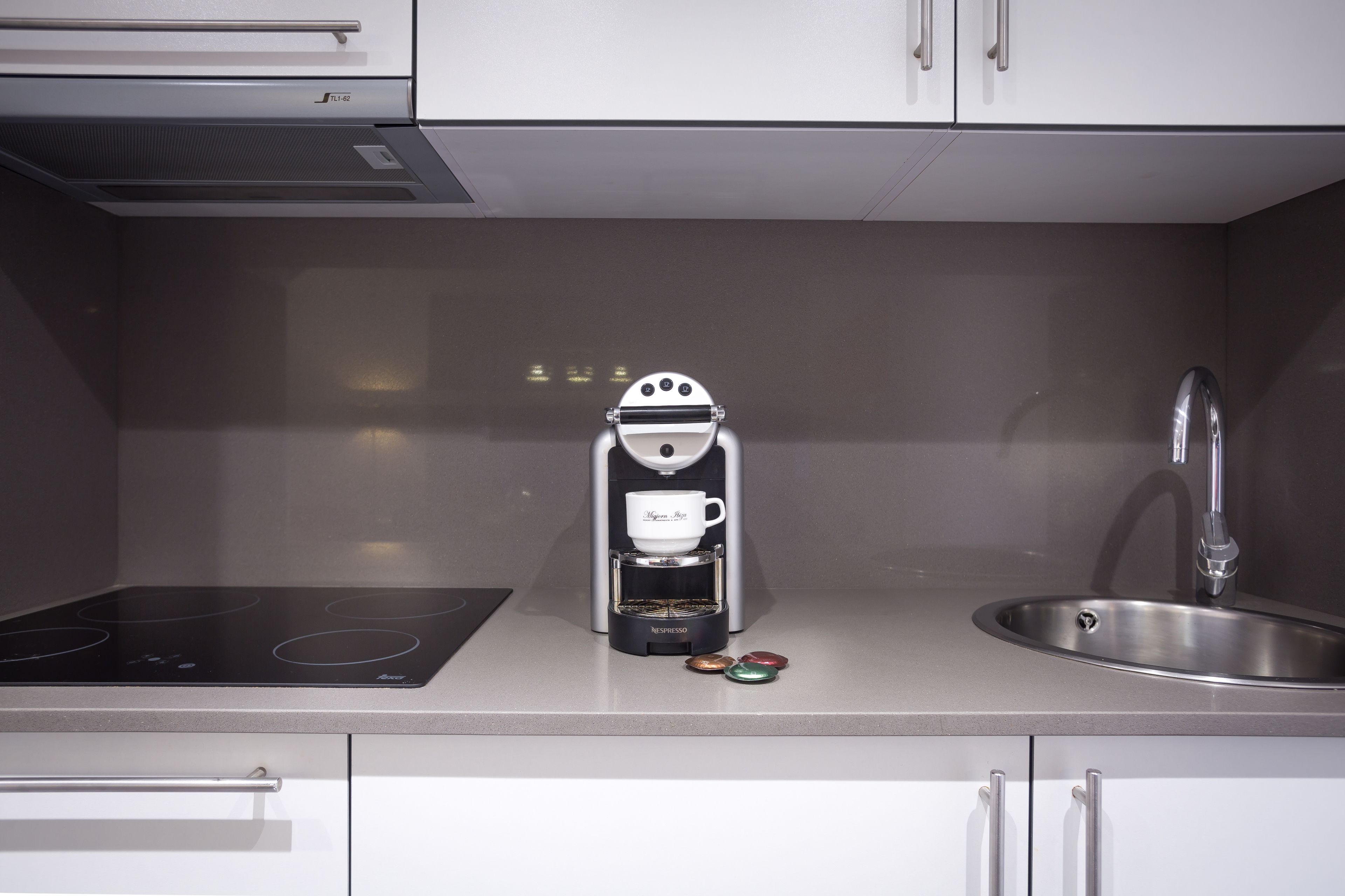 Een moderne keuken met een ingebouwde espressomachine, een spoelbak en een kookplaat.
