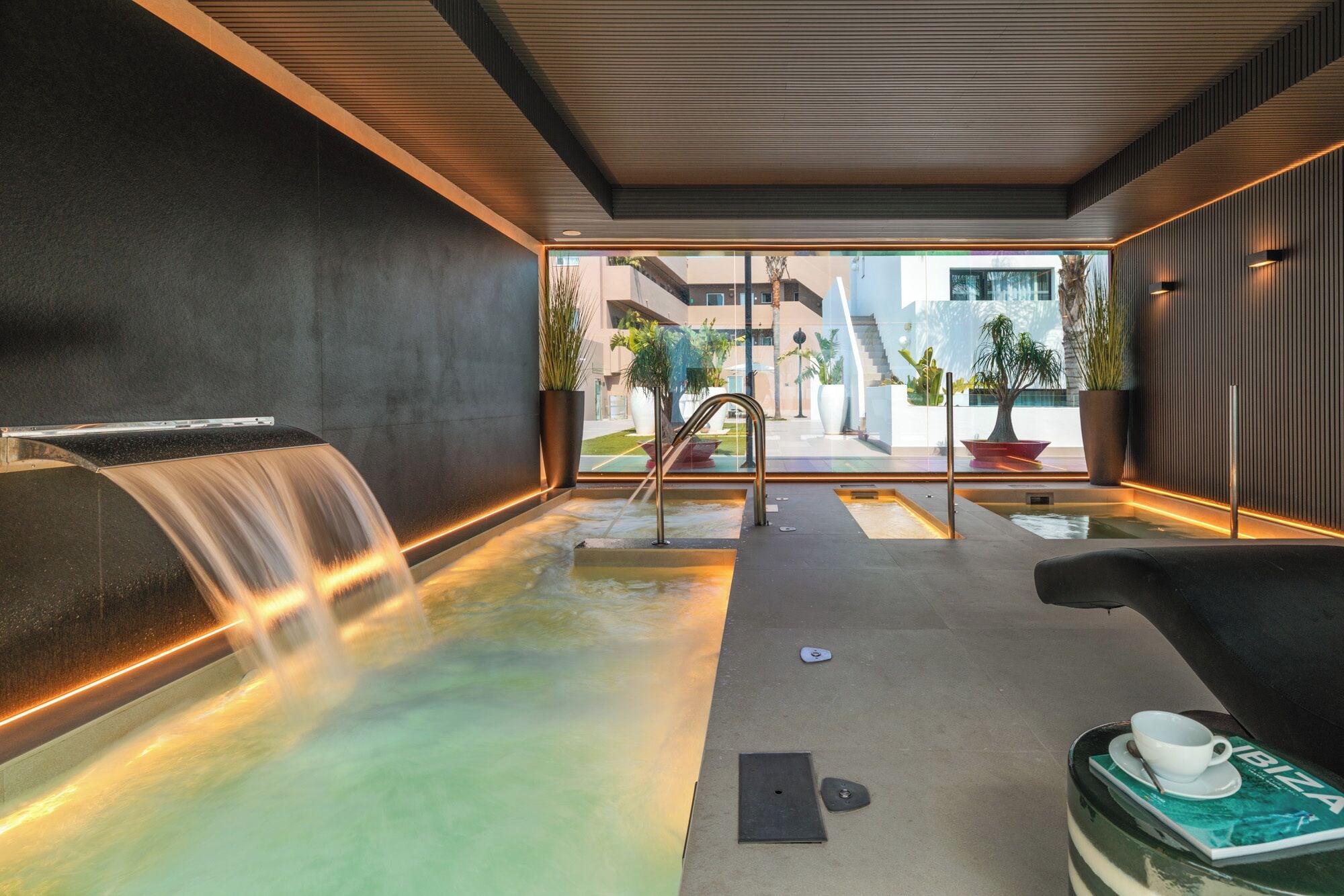 Un área de spa con una fuente de agua, asientos y vistas al exterior.
