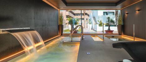 Un área de spa con una fuente de agua, asientos y vistas al exterior.