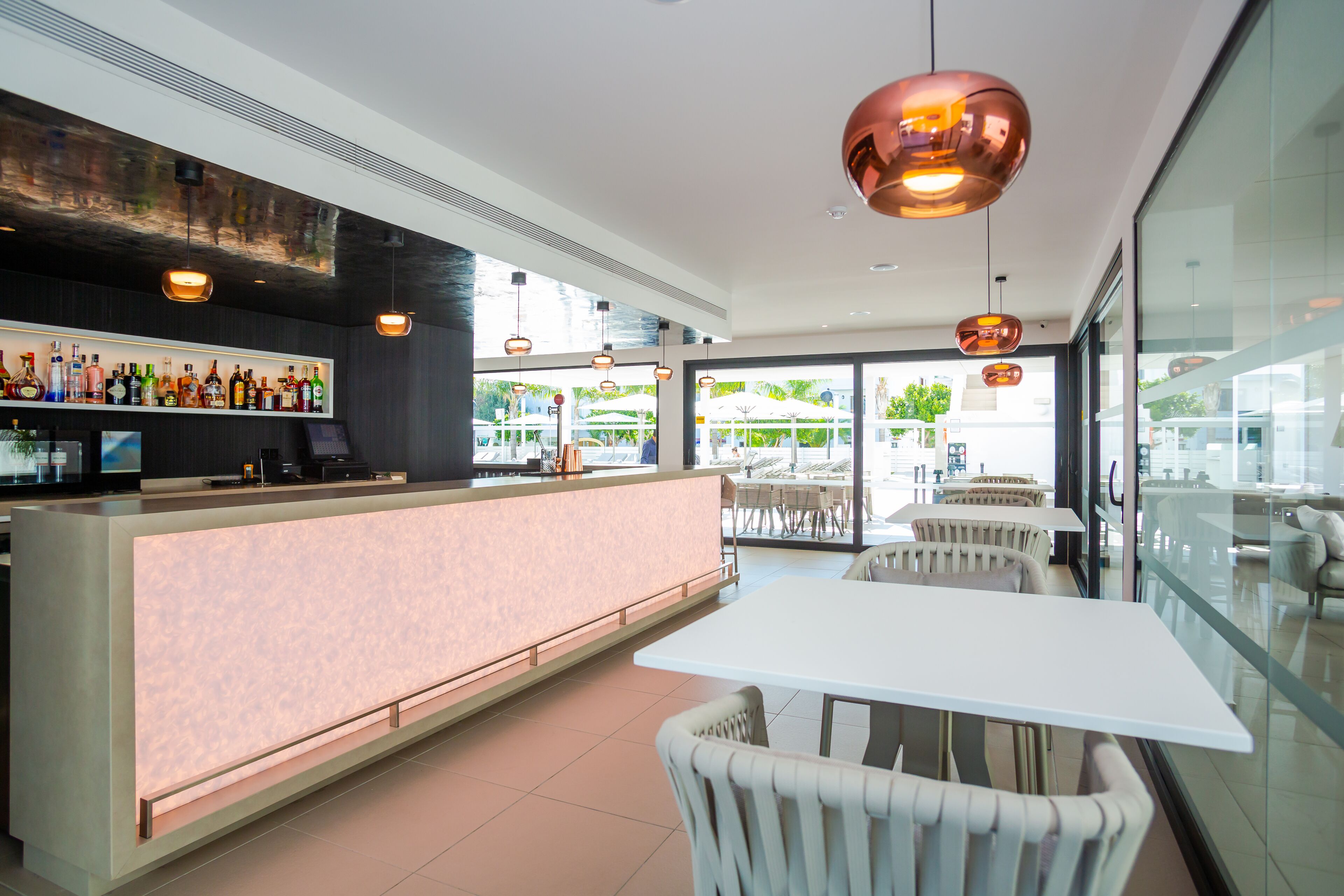 A modern bar area with a counter, seating, and pendant lighting.