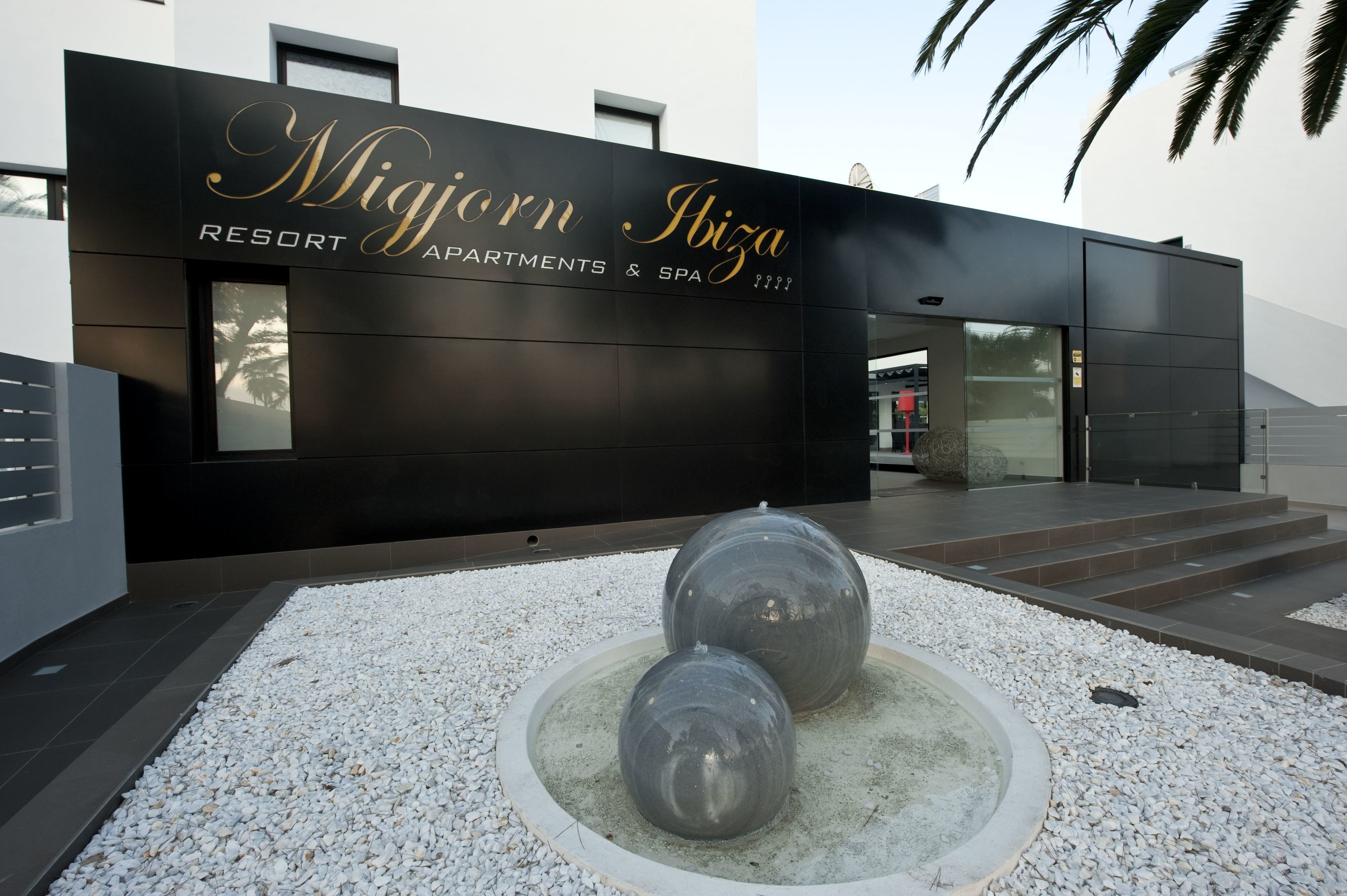Un edificio moderno con un letrero que dice "Migorn Ibiza RESORT APARTMENTS & SPA".