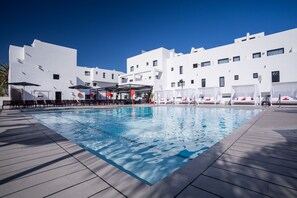 A modern pool area with a clear blue pool, white buildings, and sun loungers. - Migjorn Ibiza Suites & Spa (Sant Josep de sa Talaia)