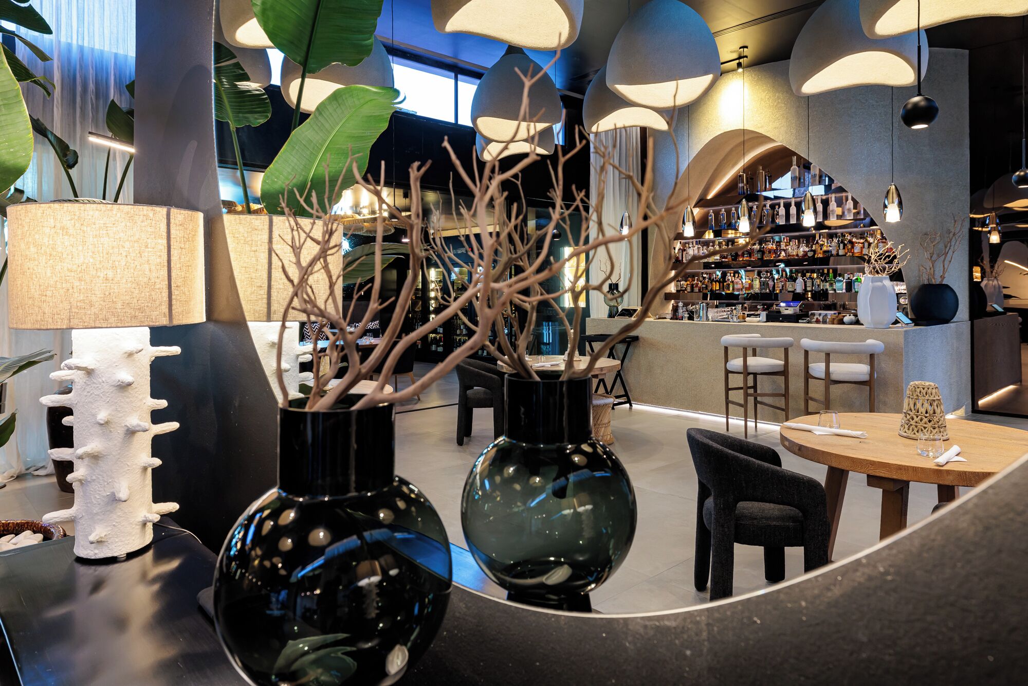 A modern interior with round tables, chairs, and decorative vases.