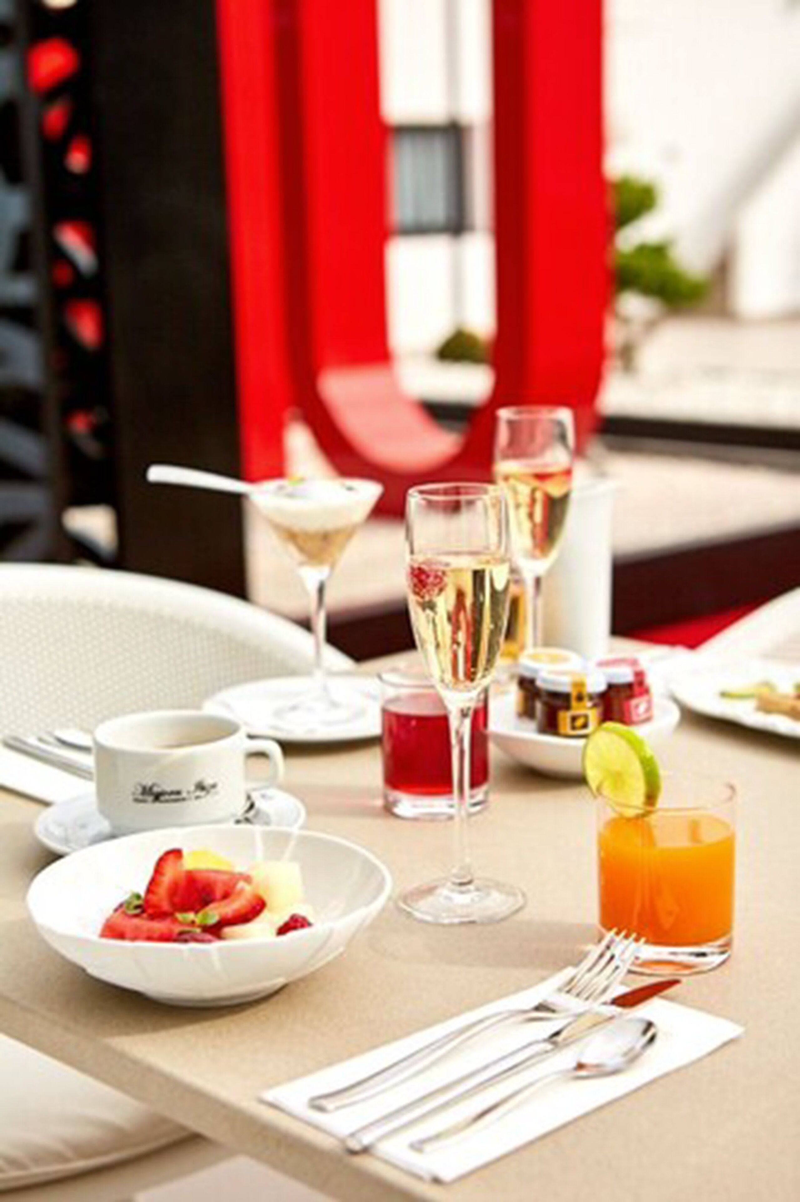 A table set with a bowl of fruit, a glass of orange juice, and a martini glass.