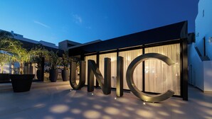 A modern building with large metallic letters spelling 'UNIC' on the facade. - Migjorn Ibiza Suites & Spa (Sant Josep de sa Talaia)