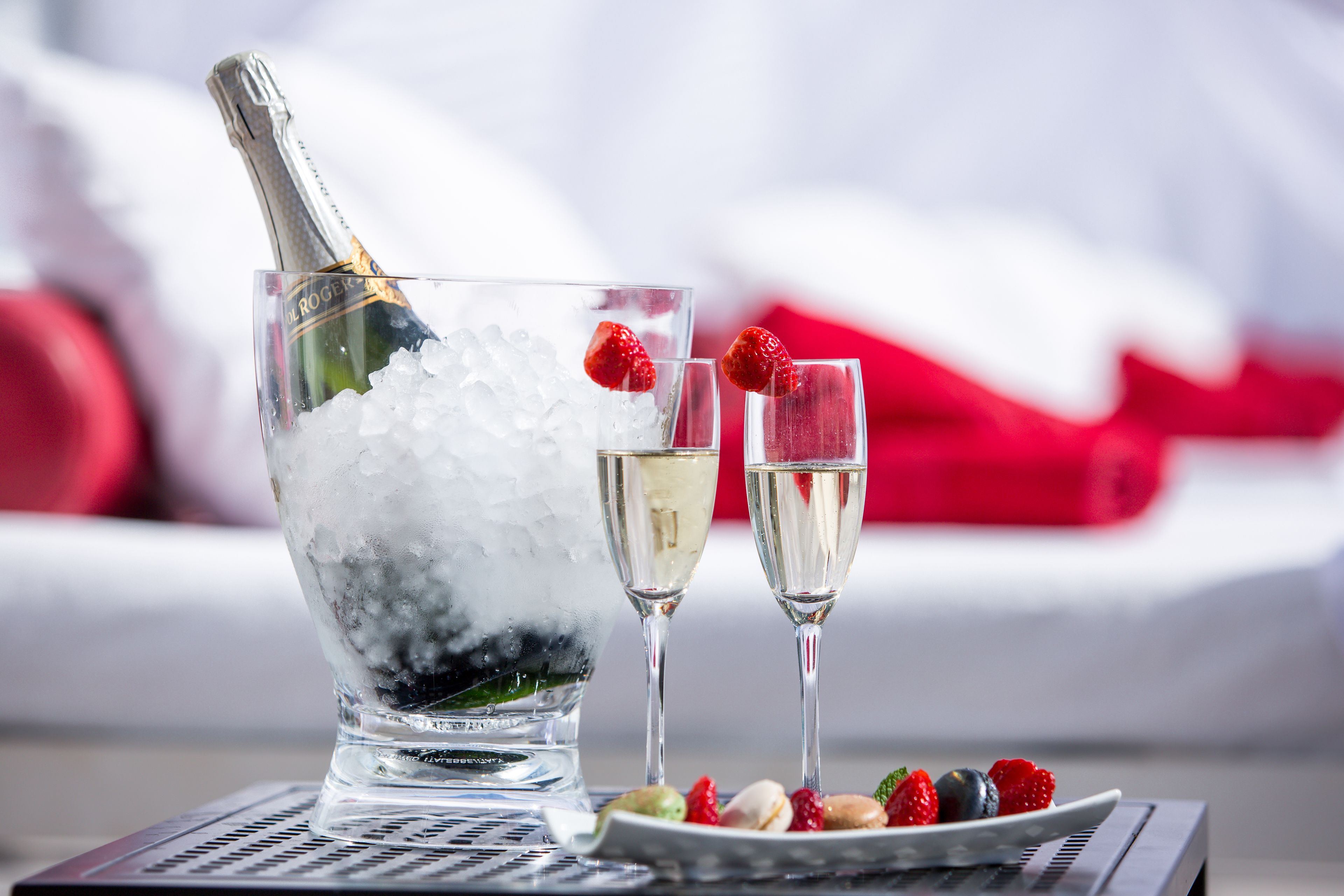 Ein Kübel mit Champagner, zwei Gläsern, Eiswürfeln und Erdbeeren.