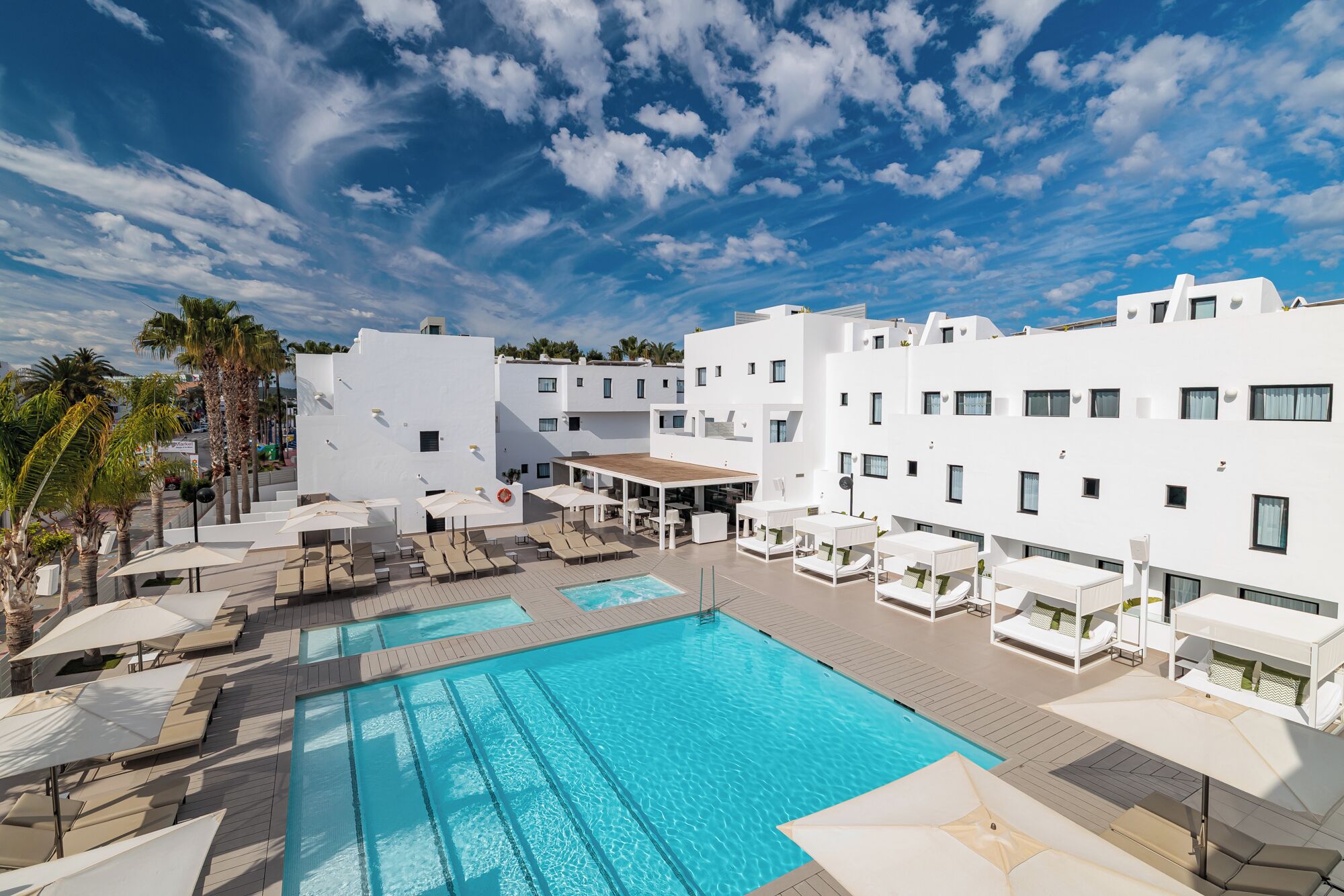Un resort con piscina, sillas de descanso y edificios blancos.
