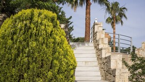 A staircase with stone walls and metal railings, leading up to a palm tree. - Athina Luxury Villas (Platanias)