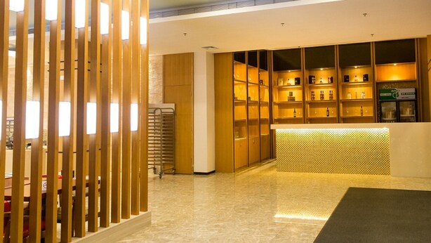 A reception area with a wooden partition, a tiled floor, and a reception desk with shelves of items. - ibis Dongguan Dongcheng (Dongguan)