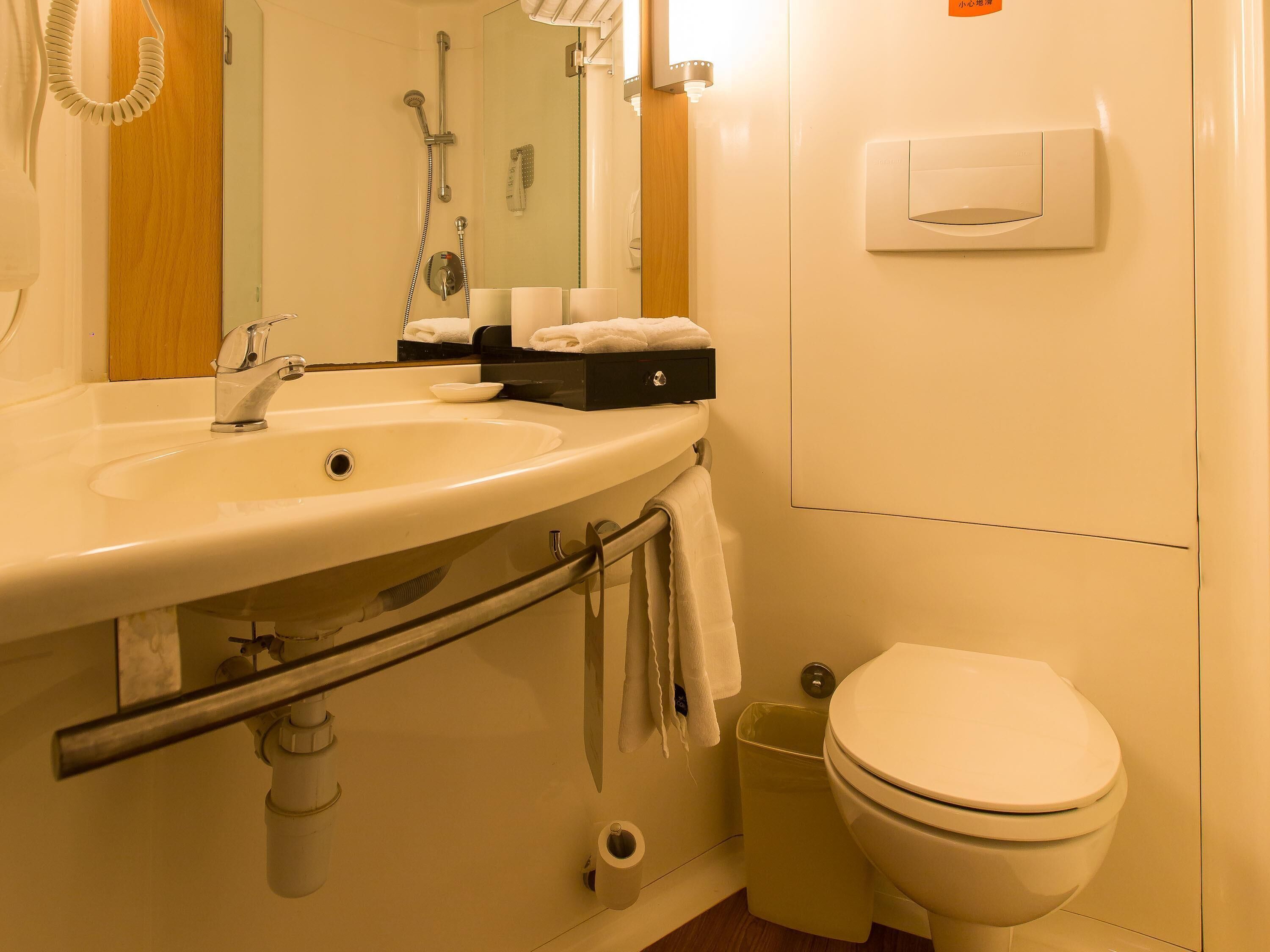Une salle de bain équipée d’un lavabo, d’un miroir, d’un porte-serviettes et de toilettes.