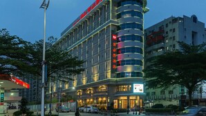 A multi-story hotel with a curved facade, illuminated signage, and a prominent entrance. - ibis Dongguan Dongcheng (Dongguan)