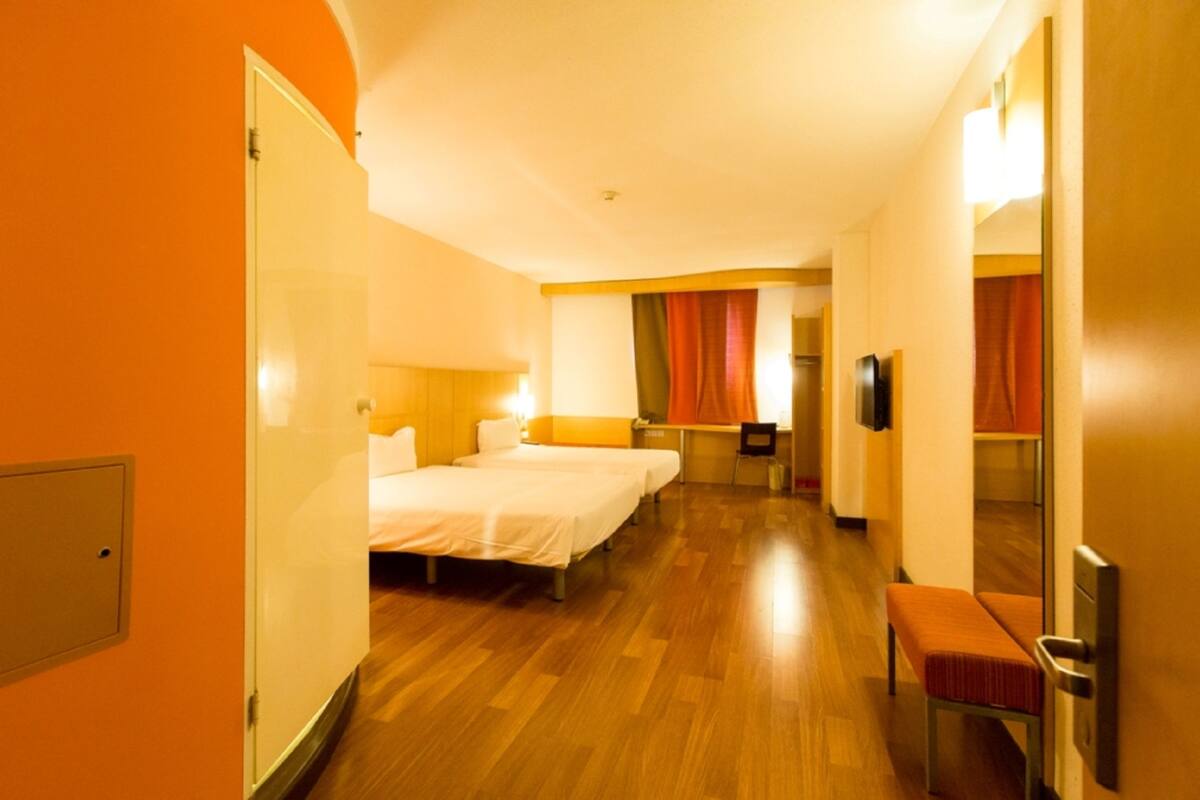 Een hotelkamer met twee bedden, een bureau, een stoel en een bank.