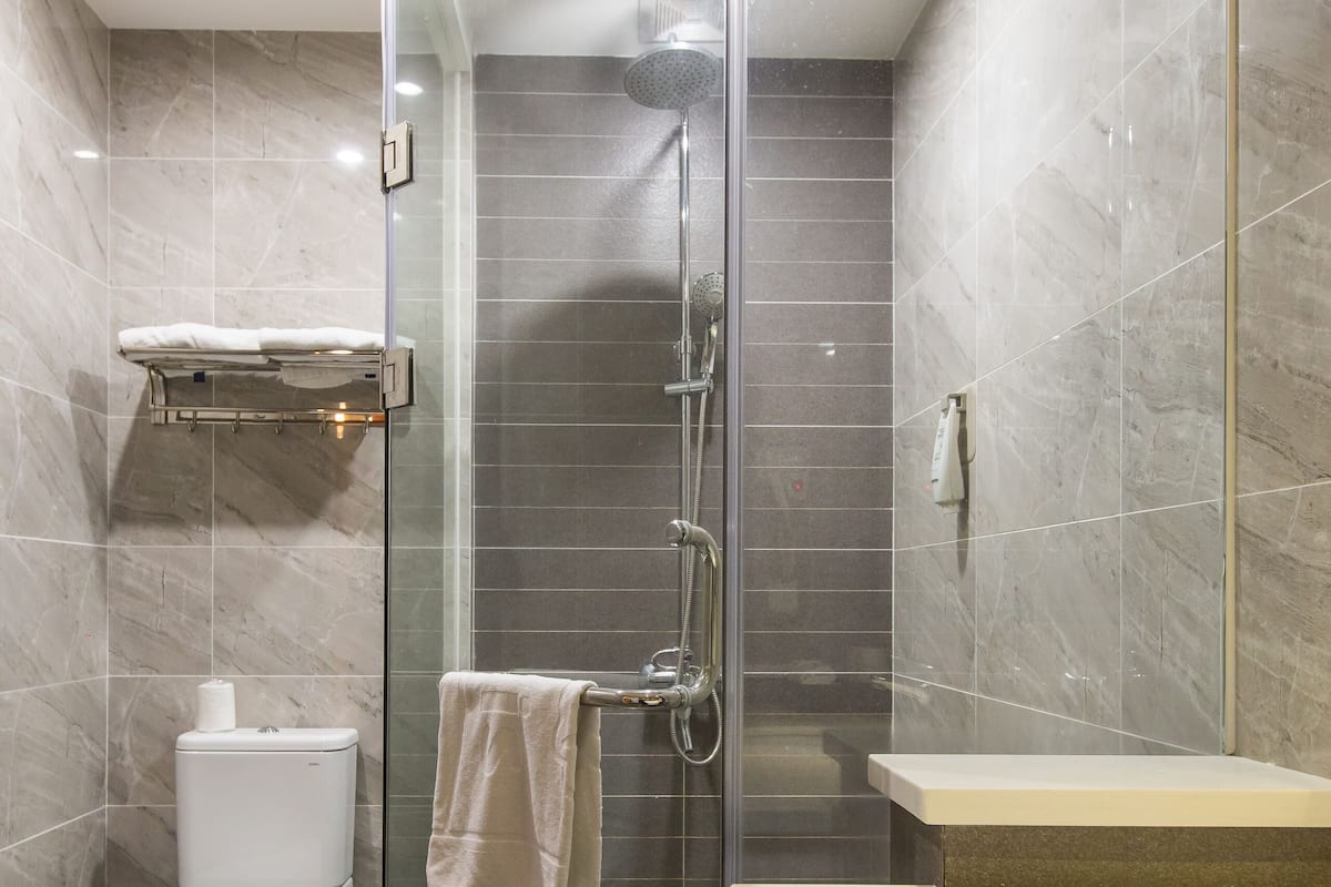 Een moderne badkamer met een douchecabine van glas, een toilet en een wastafel met spiegel.