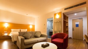 A hotel room with a bed, a sofa, a red armchair, a small table, and a wardrobe. - ibis Dongguan Dongcheng (Dongguan)