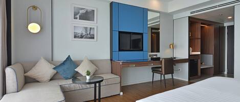 Una habitación de hotel moderna con cama, sofá, escritorio y una mesita.