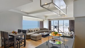 A modern hotel room with a dining area, a sofa set, and a view of the city skyline. - D Varee Jomtien Beach (Pattaya)