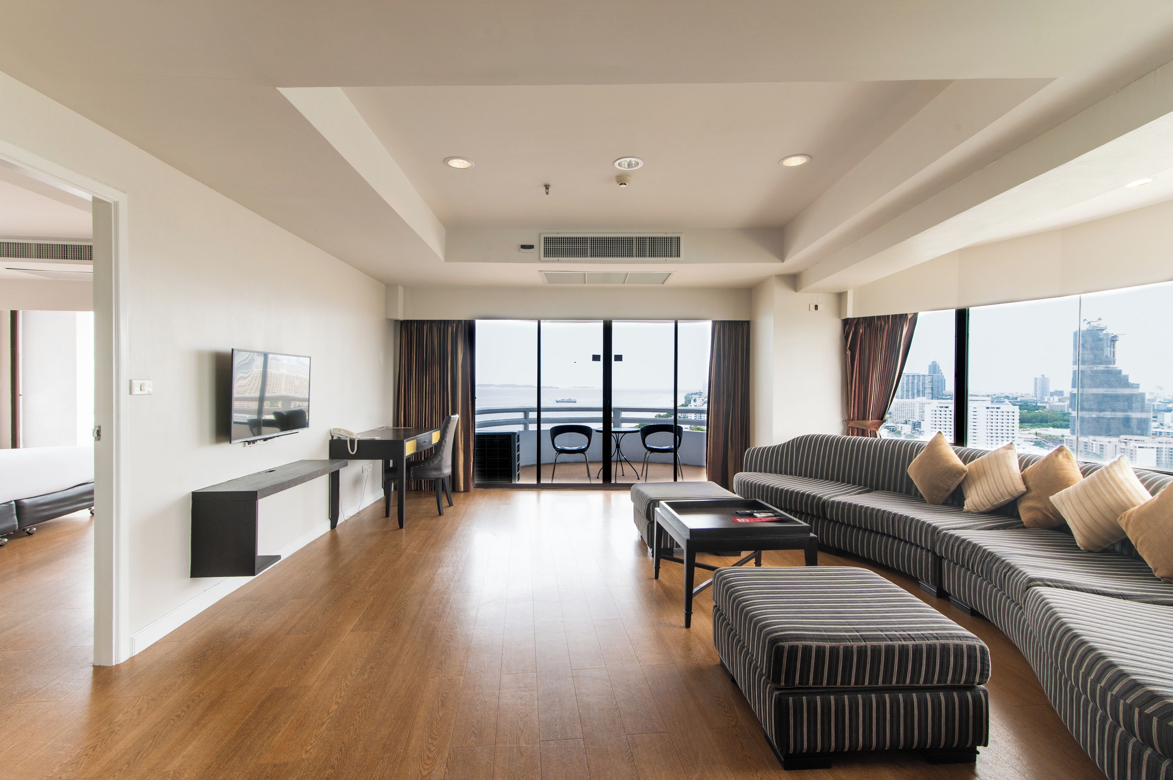 A modern living room with a sofa, ottoman, and a dining area with chairs.