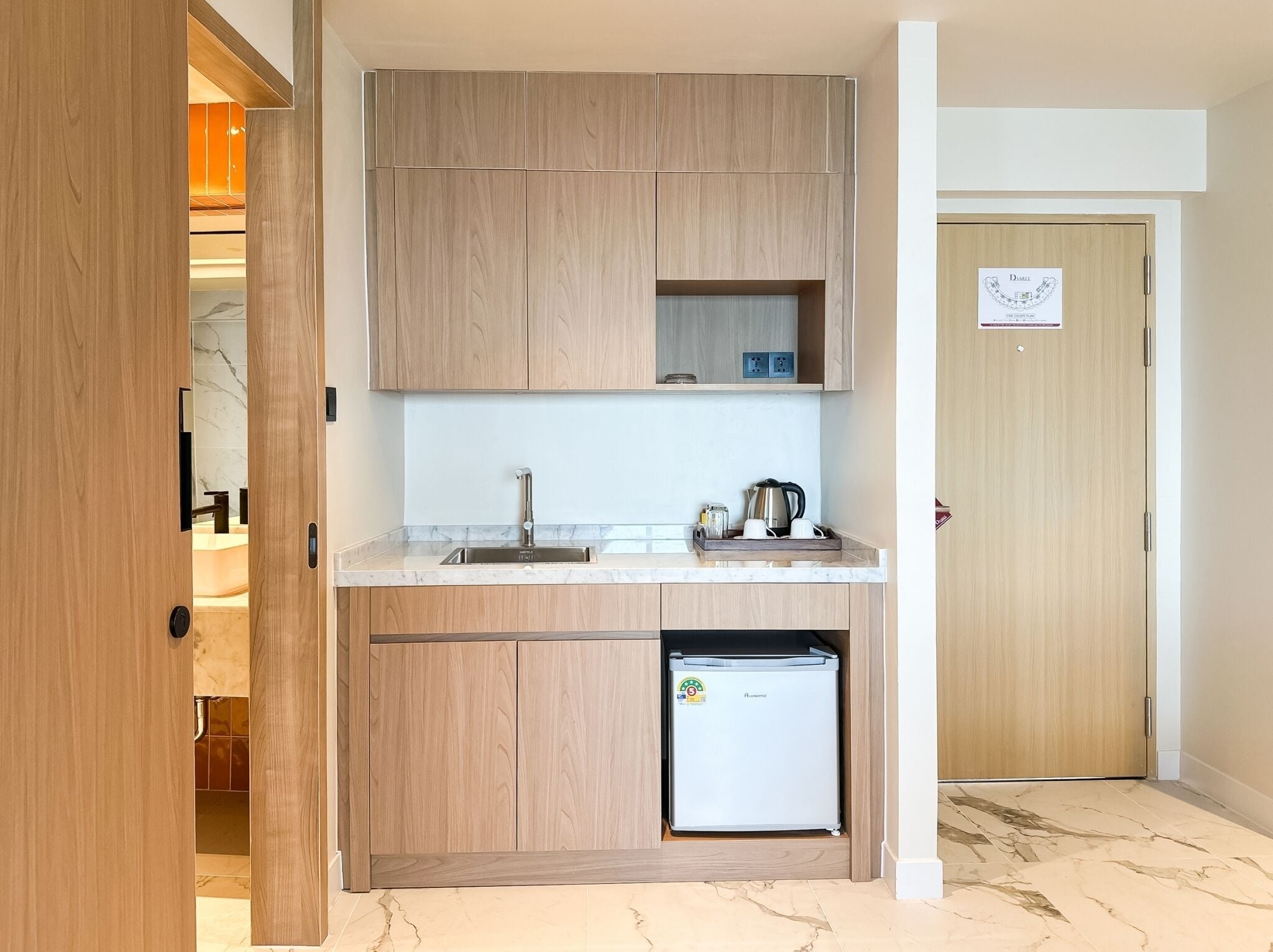 Una cocina compacta con armarios de madera, un lavaplatos integrado y un refrigerador.