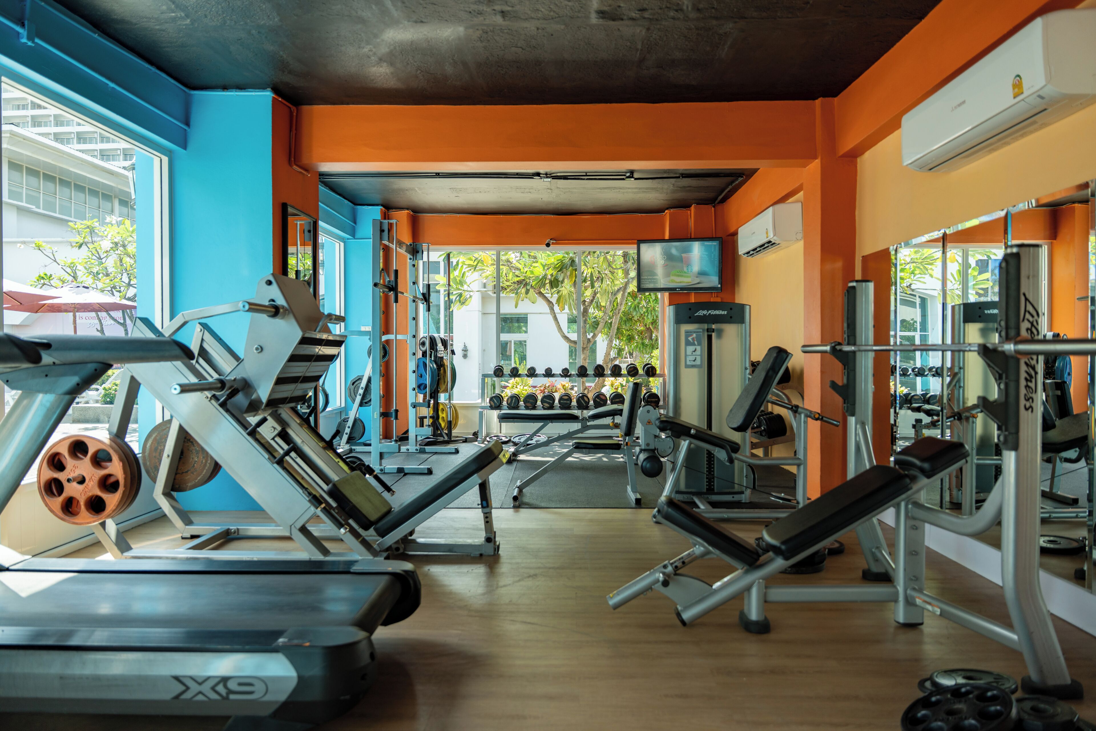 Ein Fitnessraum mit Trainingsgeräten, einem Spiegel und einem Fernseher an der Wand.