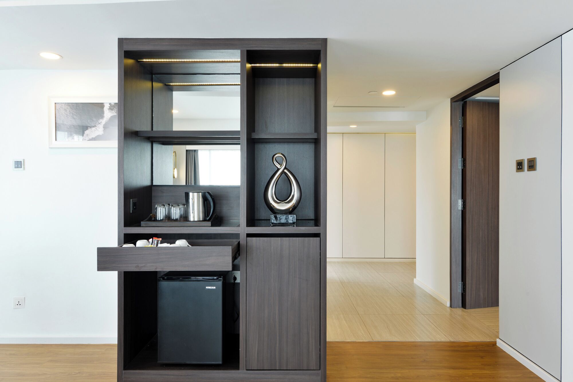 A compact kitchenette with a built-in refrigerator, a coffee maker, and a small sink.