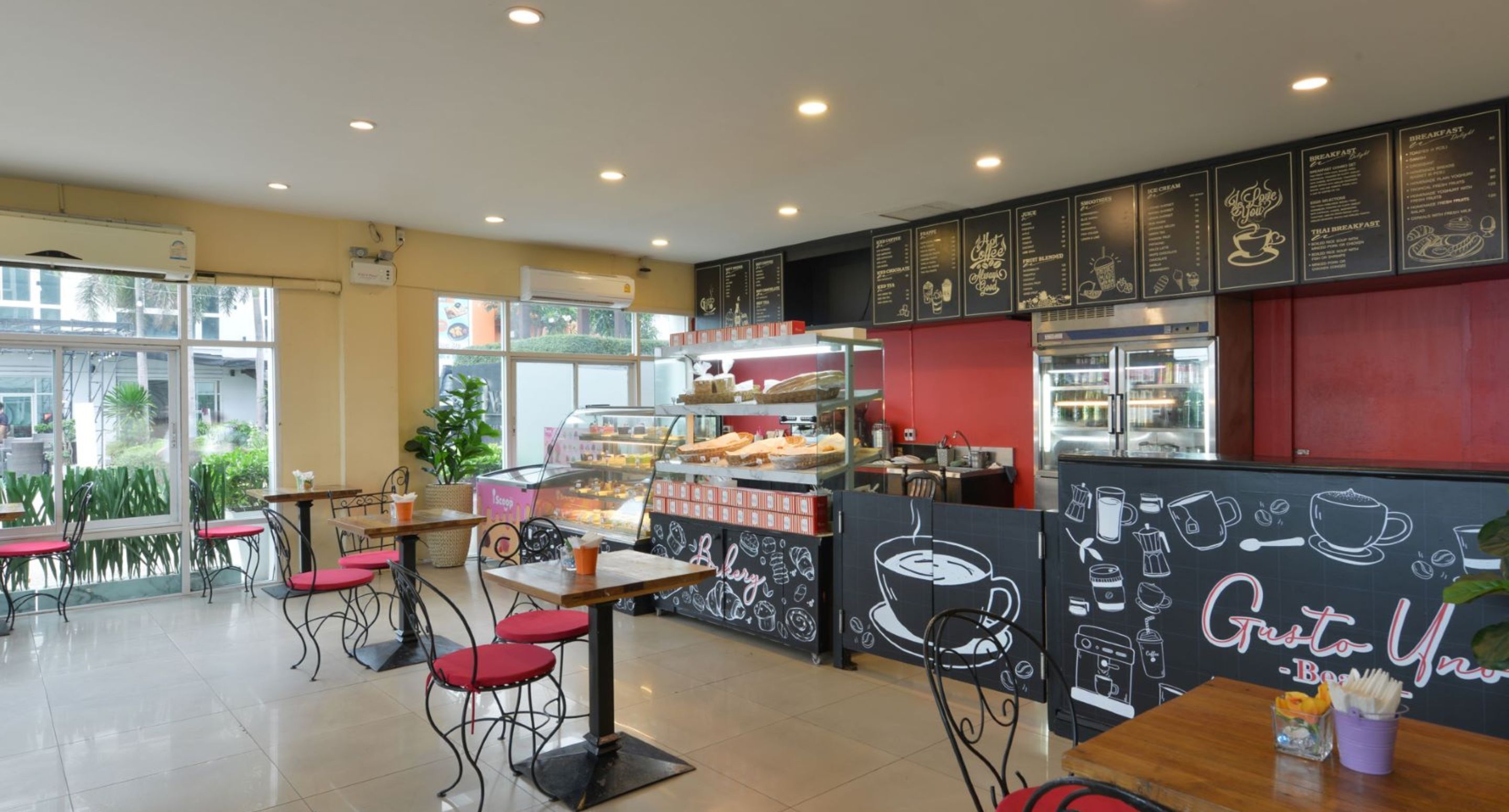 Una cafeteria amb quadre de pissarra, cadires vermelles i una màquina de cafè.