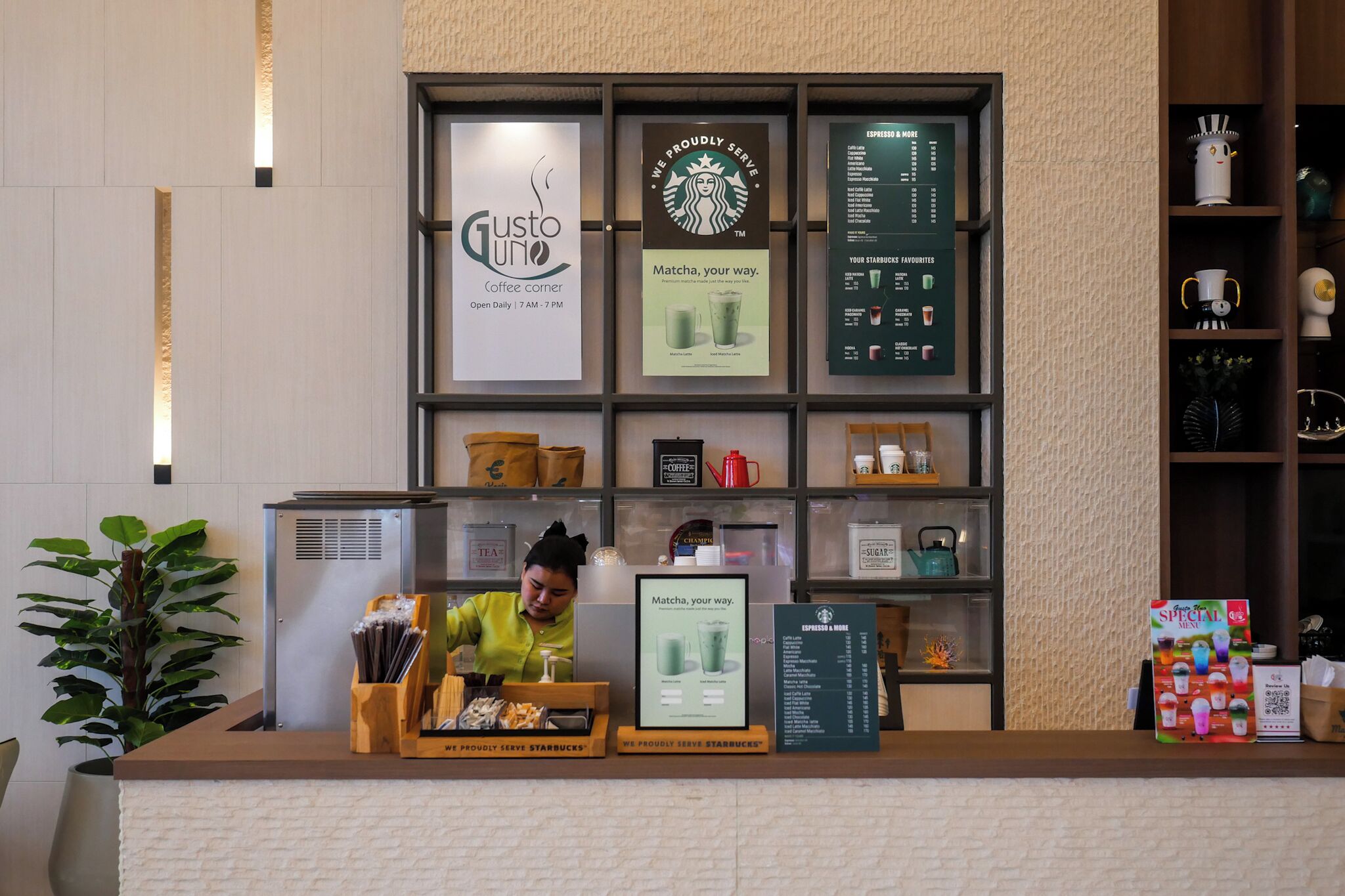 En kaffebar med en menutavle, et Starbucks logo, og en kvinde ved disken.