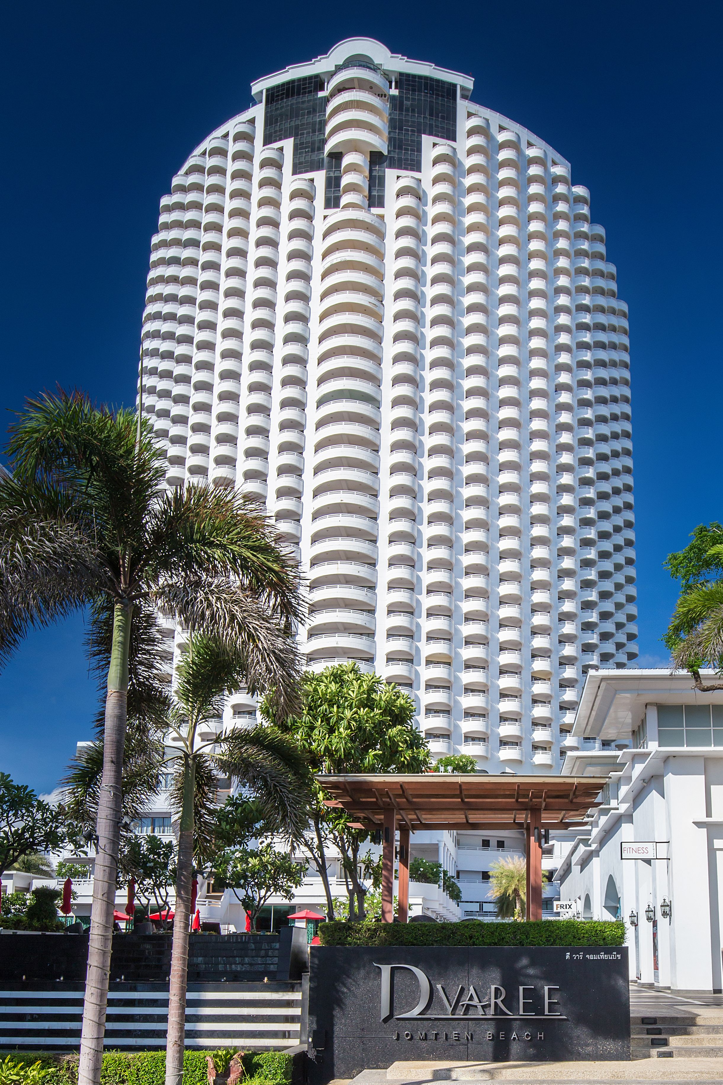 Un hotel alto y blanco, con fachada curva y numerosos balcones.