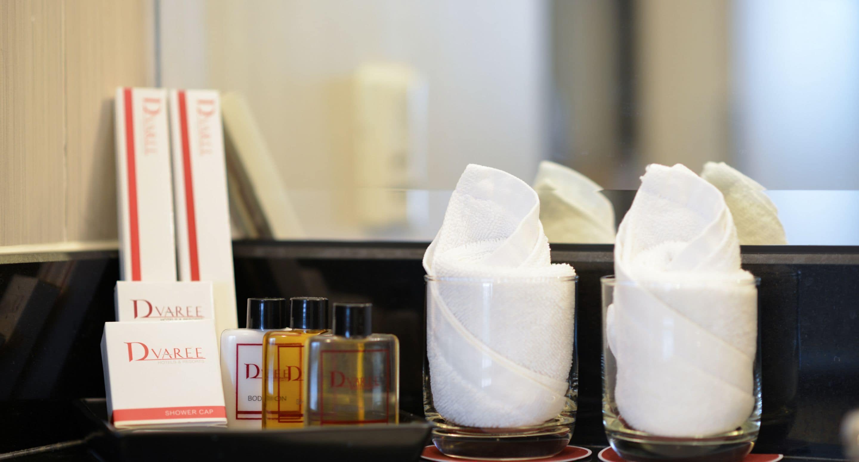 A bathroom counter with Dvarette shower cap and body lotion bottles.