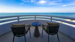 A balcony with two wicker chairs and a small round table, overlooking a beach and the sea. - D Varee Jomtien Beach (Pattaya)