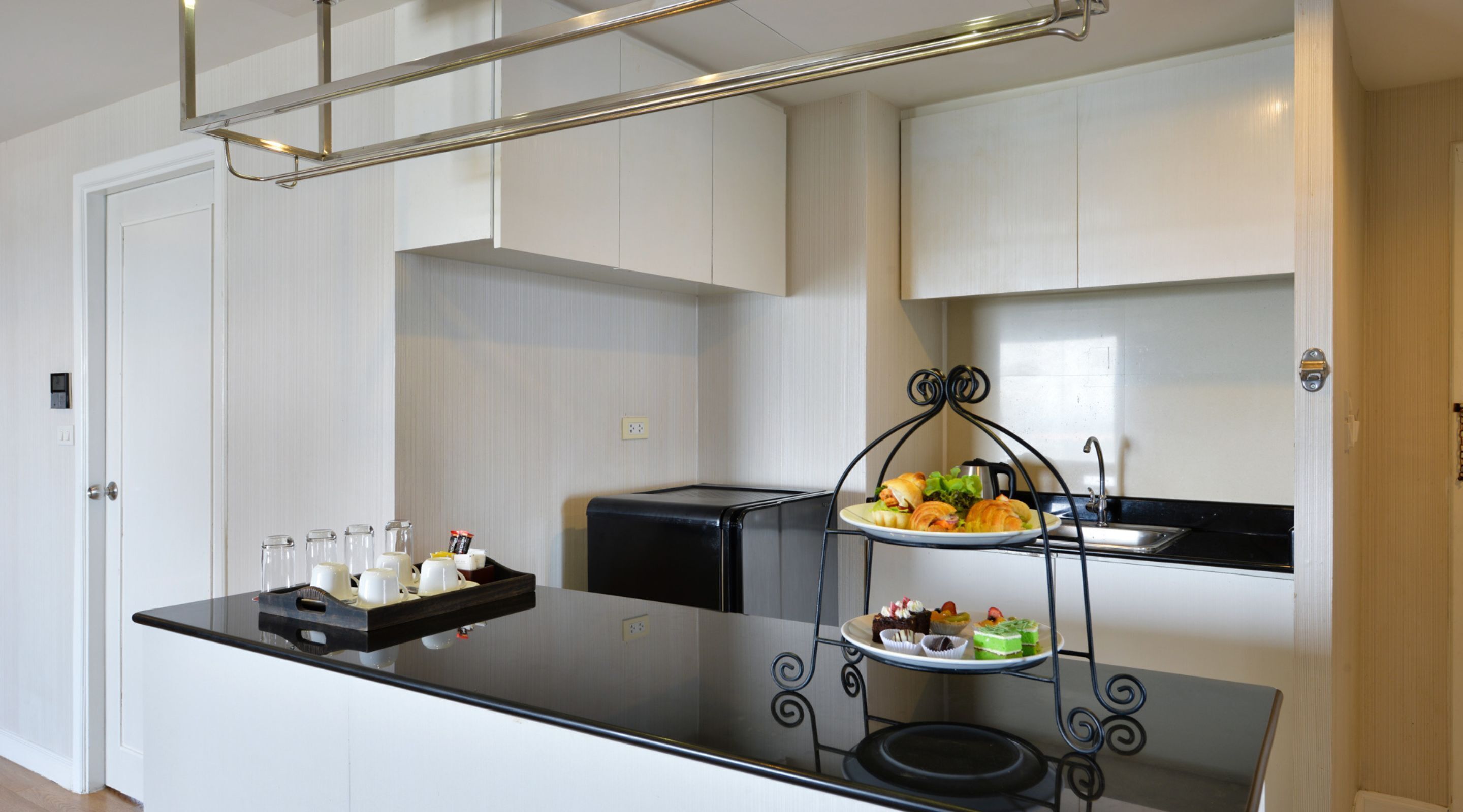 A modern kitchen with a black countertop, a three-tiered serving tray with food, and a coffee machine.