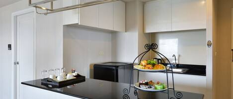 A modern kitchen with a black countertop, a three-tiered serving tray with food, and a coffee machine.