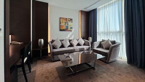 A modern living room with a sofa set, a coffee table, and a desk with a telephone. - Ramada Encore by Wyndham Doha (Doha)