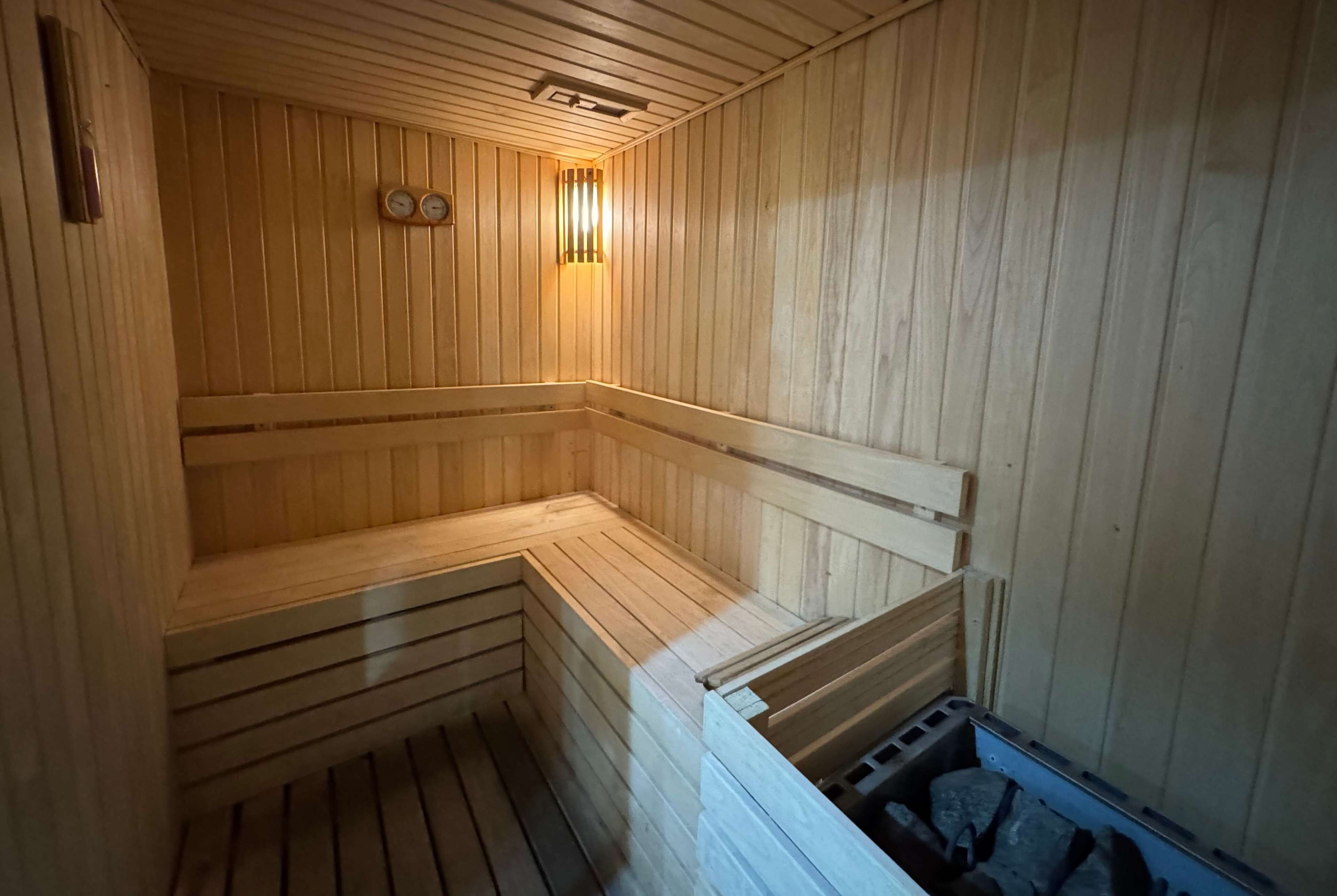 A wooden sauna with benches and a wall-mounted clock.
